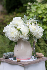 Blumenstrauß mit weißen Pfingstrosen (Paeonia) im rustikalen Krug