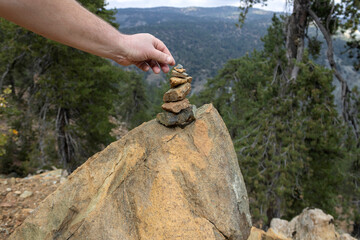 Hand creating Zen stone pyramid on big rock in mountain forest, Troodos, Cyprus