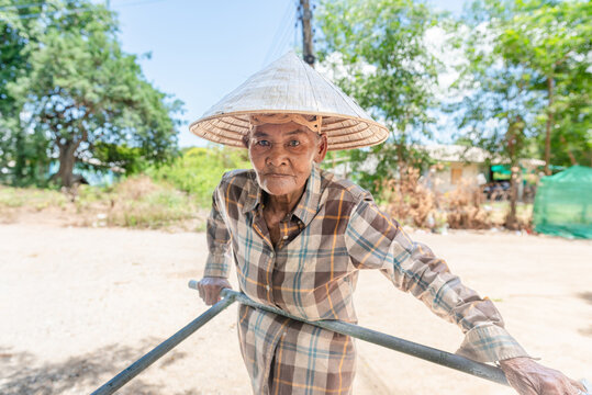 Urban Inequality: Elderly Woman Pushing a Cart in a Big City, Thailand