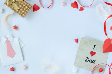 Top view of Fathers Day greeting card with paper shirt, red heart, and gift box on white background, flat lay composition for holiday celebration