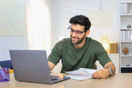 Man enjoying a productive work session from modern living space. Young man working at home. Home office., freelance. Focused handsome freelancer doing online research over laptop. 