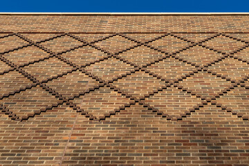 Low angle view texture background of an exterior multi-shade reddish brown color vintage brick wall surface, with diamond shape brick decoration detailing