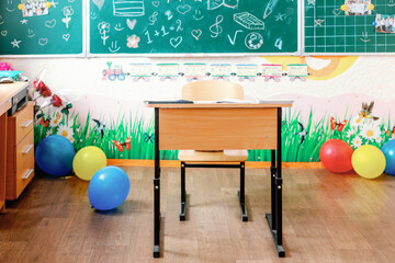 Colorful elementary classroom with decorated desk and chalkboard
