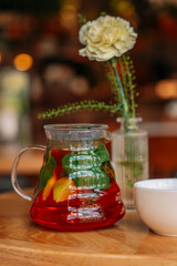 There is a teapot with rooibos tea with mint and lemon on the table in the cafe