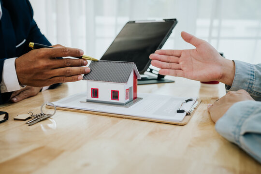 Two people exchanging house keys and signing documents, symbolizing home buying, mortgage, investment, and financial planning in real estate.