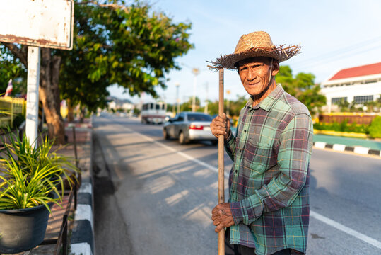 Elderly street sweeper smiling at camera in city of Thailand