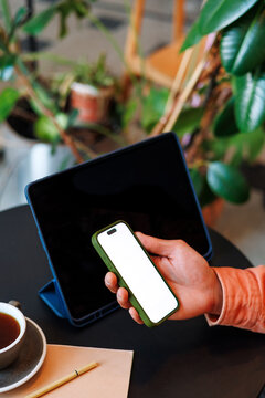 Hand Holding Smartphone with white screen by Tablet