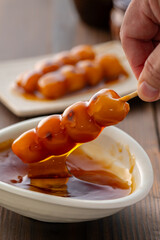 A close-up of traditional Japanese mitarashi dango—skewered rice dumplings grilled to perfection and coated with a glossy, sweet soy sauce glaze. The caramelized surface and rich glaze highlight the a