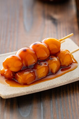 A close-up of traditional Japanese mitarashi dango&mdash;skewered rice dumplings grilled to perfection and coated with a glossy, sweet soy sauce glaze. The caramelized surface and rich glaze highlight the a