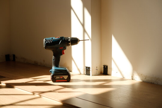 Cordless power drill standing on wooden floor during home renovation