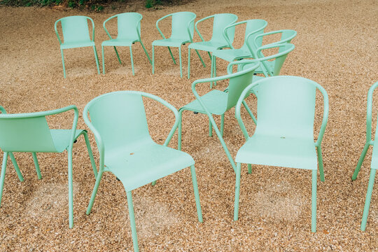 Outdoor circle of green chairs arranged on gravel in public park