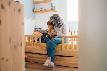 Grandmother reading a story to grandson in bedroom