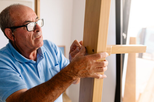 Retired man installing screws to assemble new furniture