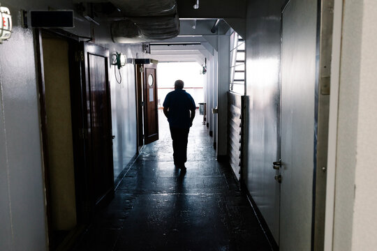 Silhouette of an old man walking through a ship during an ocean voyage