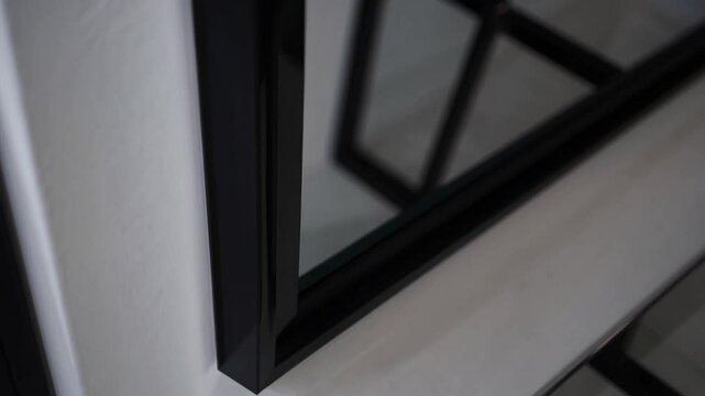 Minimalist black frame mirror reflecting modern interior style, calm and elegant atmosphere with blank frame, glass table