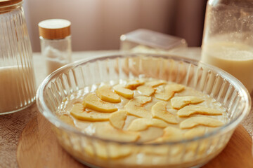 A close-up shows a glass pie dish filled with batter and neatly arranged apple slices, ready for baking.