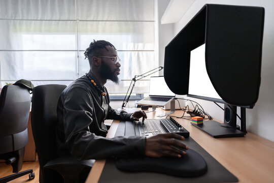 Video editor working from home using professional monitor and keyboard