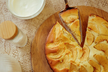A close-up, top-down view shows a slice being lifted from a freshly baked apple pie on a wooden...