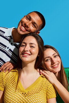 Friends enjoy a playful moment together against a bright blue ba