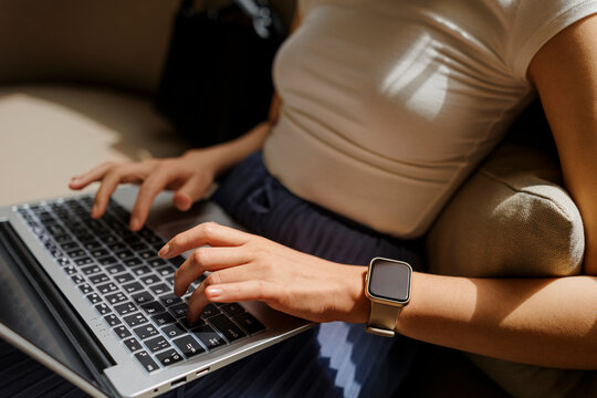 Freelancer wearing smartwatch working on laptop - Powered by Adobe