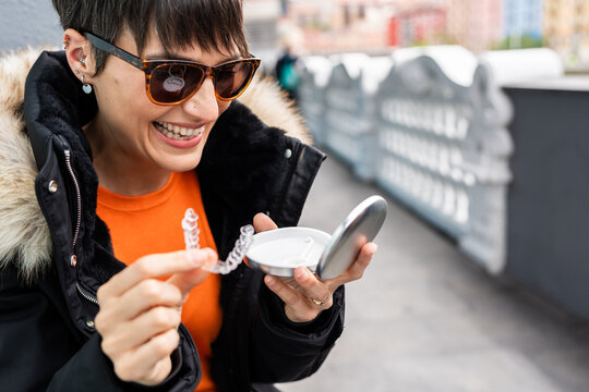 Woman smiling holding invisible braces and their box in the city