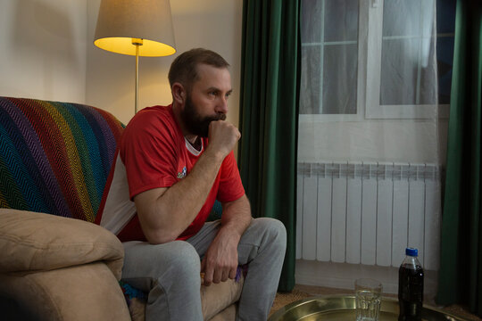 Football fan watching match at home, feeling tense