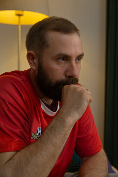 Football fan watching match at home, biting his nails in suspense