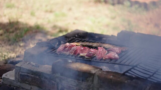 Grilling delicious Skirt steak and Top Sirloin Cap over open flame on an outdoor barbecue with smoke rising.