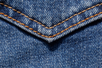 close up of seam with orange thread on pocket of blue jeans