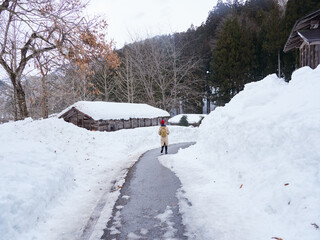 冬の世界遺産の白川郷の合掌造りの雪景色と女性観光客の姿