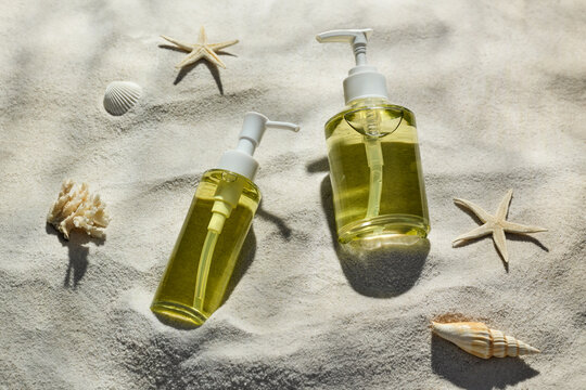 A serene coastal scene featuring bottles of soap amid shells on sand