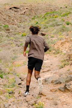 Professional trail runner climbing a rocky trail during a sunny day