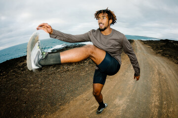 Flash-lit angular sports photograph of a trail runner doing warming-up