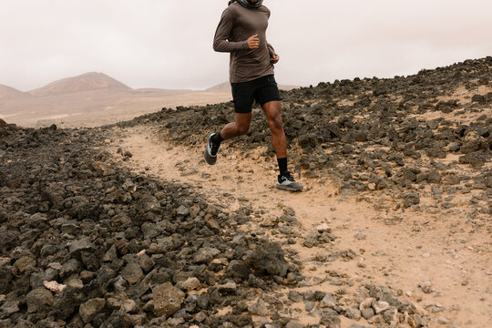 Unknown man trains by hiking through a rugged valley - Powered by Adobe