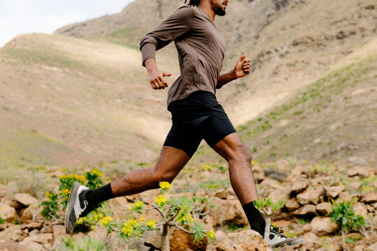 Unidentified man sprints along a gravel path in a mountainous region