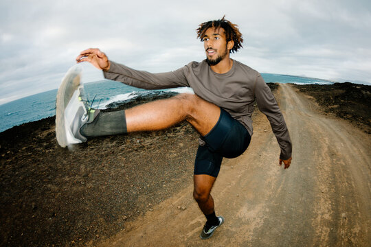 Flash-lit angular sports photograph of a trail runner doing warming-up