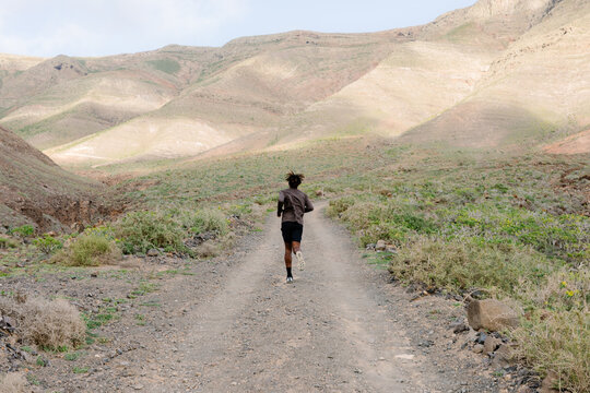 Wide shot of a lone runner on a winding dirt road