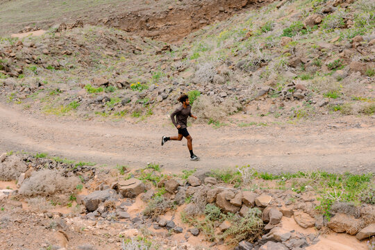Wide shot of a lone runner on a winding dirt path