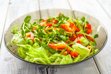 Fresh vegetable salad with micro greens and red pepper in a transparent bowl. Concept of healthy nutrition using for cookbook or food blog.