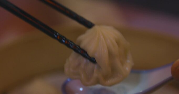 Xiao long bao in the steamer basket with chopsticks at dinner handheld shot