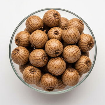 Whole baheda fruits in transparent glass bowl isolated on white background