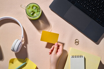 Overhead shot of workspace with a hand holding credit card and laptop