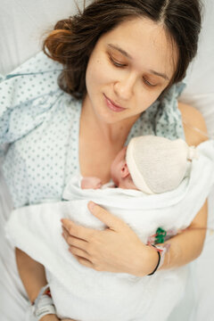 Newborn cradled by mother in hospital setting