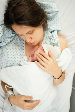 Newborn cradled by mother in hospital setting