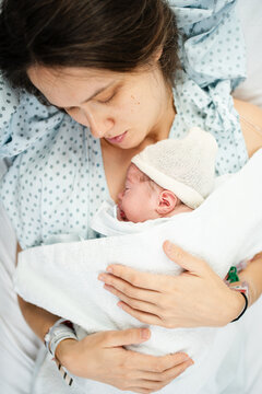 Newborn cradled by mother in hospital setting
