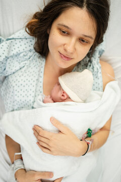Newborn cradled by mother in hospital setting