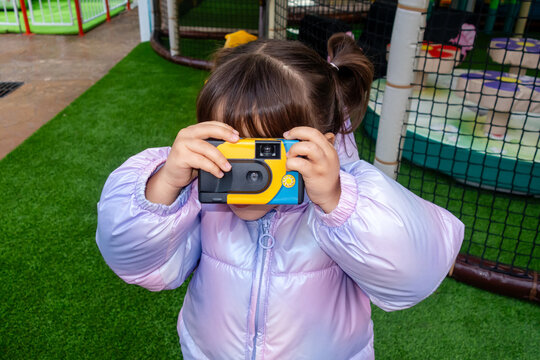 Little girl taking pictures with disposable camera in playground