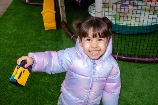 Happy smiling preschool girl playing with toy camera in playground