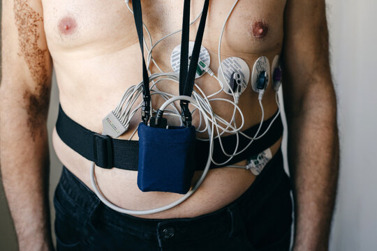 Elderly man with a Holter monitor against a light wall.