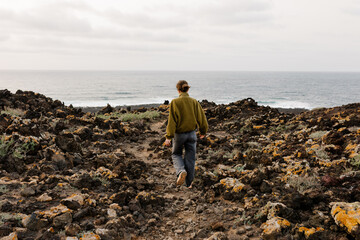 Full body shot of a woman enjoying a stroll along a rocky path